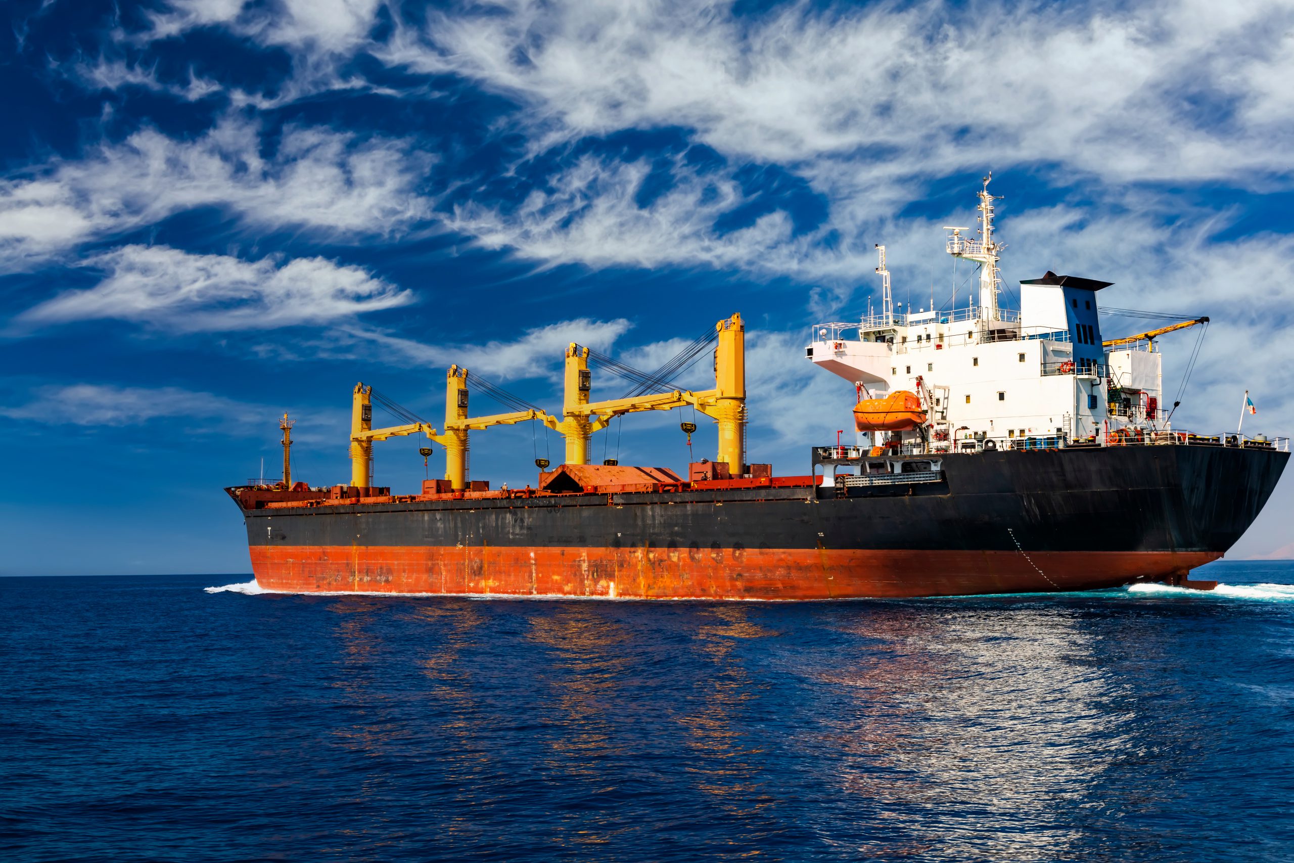 Cargo ship at sea against the blue sky. Logistics and cargo transportation